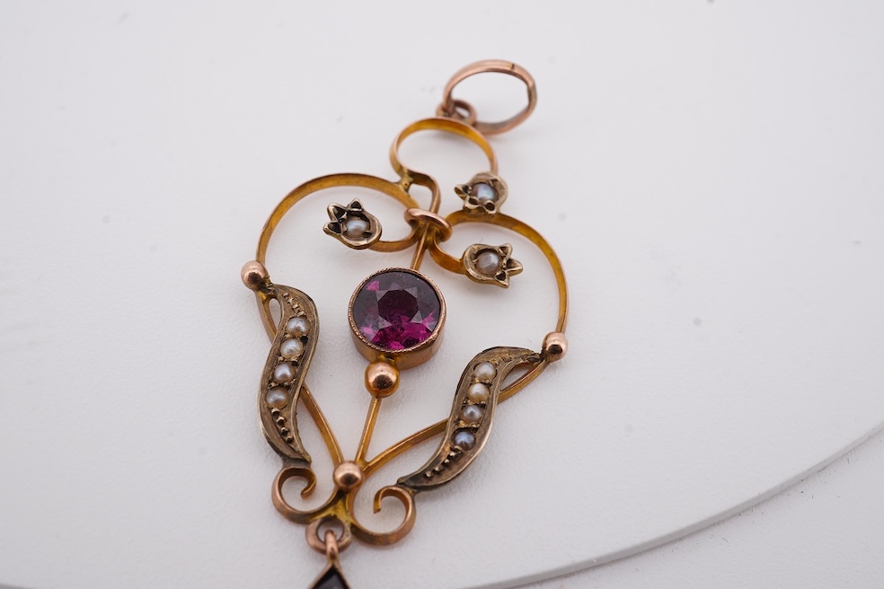 An Edwardian 15ct, diamond and seed pearl cluster set stick pin, 54mm, a similar yellow metal and cabochon garnet set stick pin and an Edwardian 9ct and gem set drop pendant. Condition - poor to fair